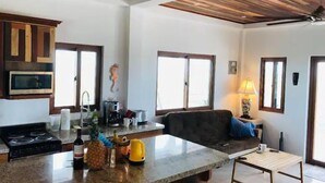 Una cucina con piano di lavoro in granito, fornello e forno a microonde. Si vede una finestra con vista all'esterno.