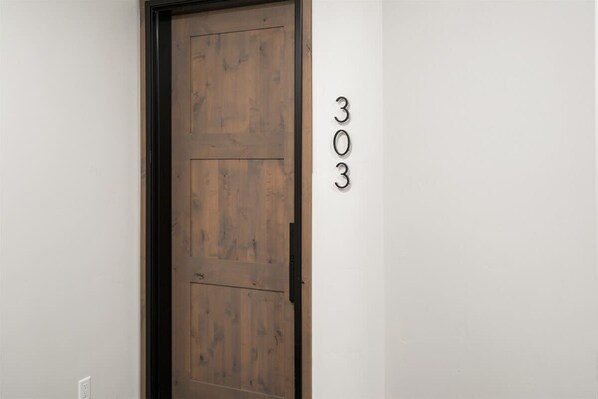 A wooden door with the number 303 on the wall beside it.