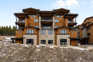 A multi-story building with a stone facade and wooden accents, featuring balconies and large windows.