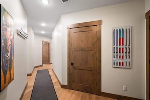 A hallway with a wooden door, a black mat, and a ski-themed wall art.