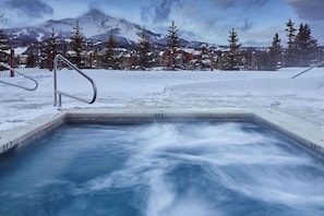 Ein Whirlpool in verschneiter Outdoor-Umgebung mit Bergkulisse.