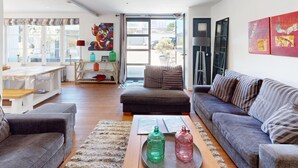 Um espaço de estar moderno com sofá, mesa de centro e área de jantar com mesa e cadeiras.