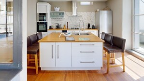 Uma cozinha moderna com ilha central, armários brancos e uma janela grande.