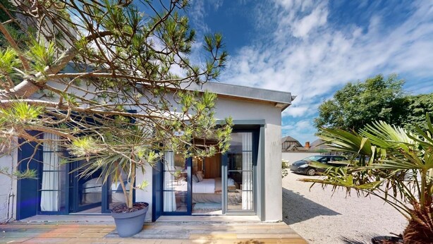 Uma casa moderna com um deck de madeira, porta de entrada de vidro e um vaso com planta.