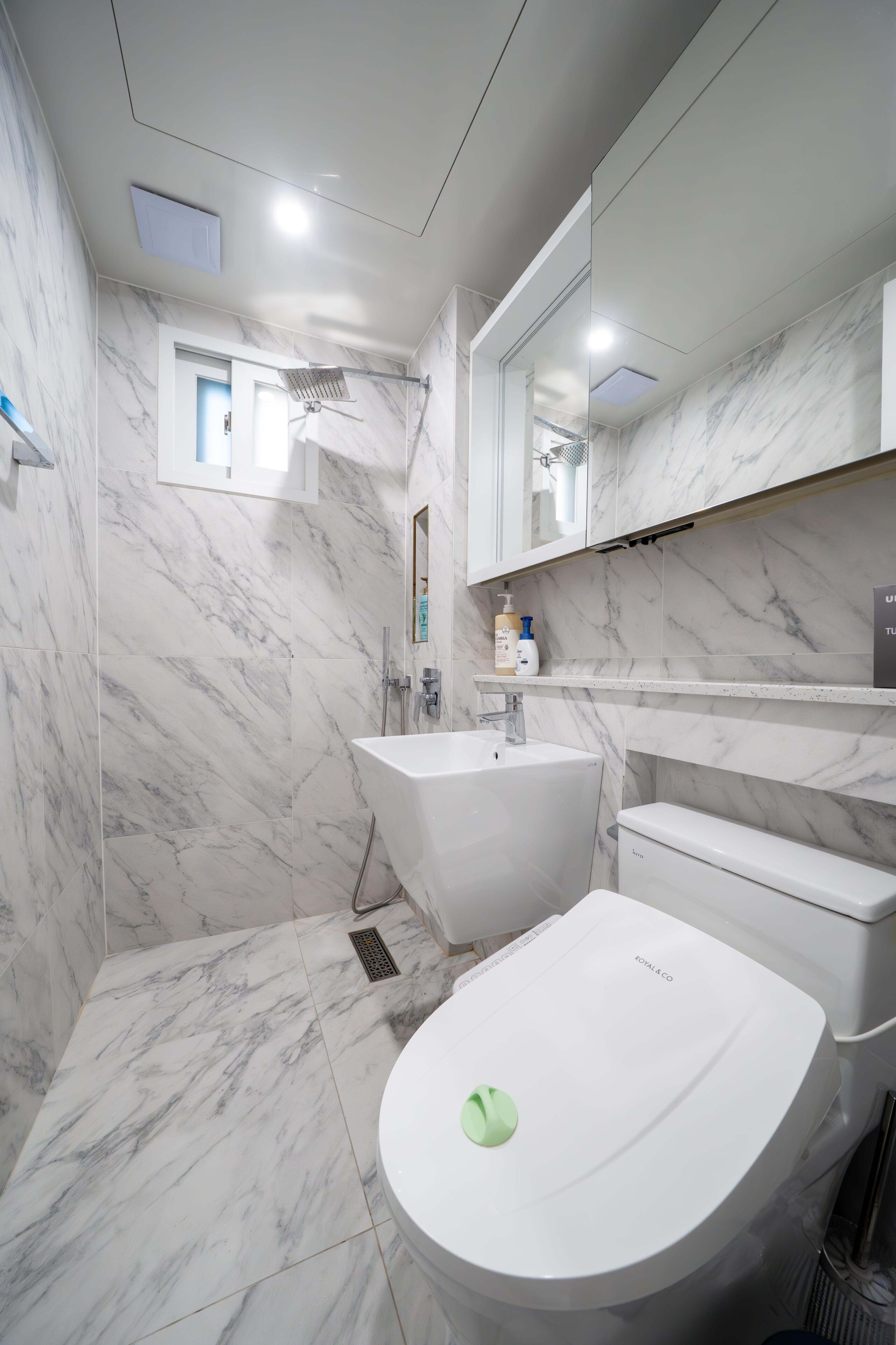 A modern bathroom with a marble floor, a bathtub, a toilet, and a sink.