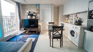A modern apartment with a dining area, kitchen, and a large window with a view.
