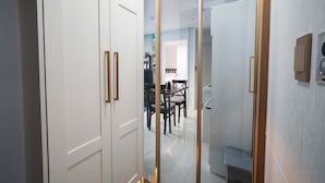 A hallway with a glass partition leading to a dining area with a table and chairs.