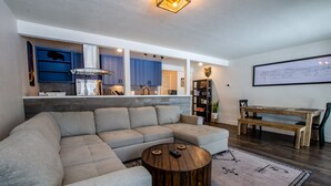 Una sala de estar moderna con un sofá modular, una mesa de centro redonda de madera y un comedor con un banco.
