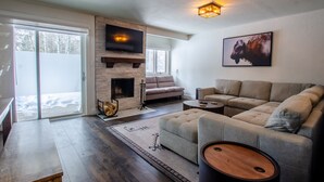 Una sala de estar moderna con chimenea, un sofá, una mesa de centro y un televisor montado en la pared.
