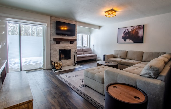 A modern living room with a fireplace, a sofa, a coffee table, and a TV mounted on the wall.