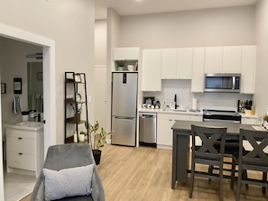Enjoy meals in the dining area with a dark wood table and chairs, adjacent to the compact kitchen with stainless steel appliances.