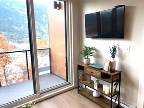 Enjoy a contemporary space with a large sliding glass door leading to a balcony, a flat-screen TV, and a minimalist console table.