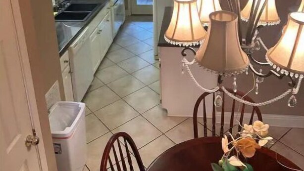 Un coin repas agrémenté d’un lustre, d’une table avec des chaises et d’une vue sur la cuisine.