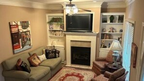 Un salon avec une cheminée, un canapé, un fauteuil et un téléviseur.