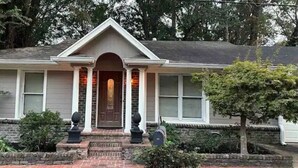 A two-story house with a central entrance, a brick foundation, and a small front yard with a tree and shrubs. - Plenty of room near square (Oxford)