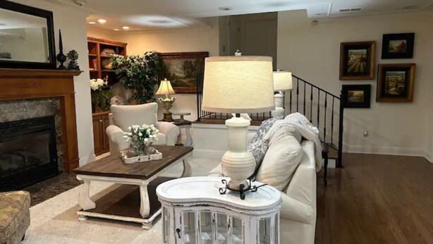 A living room with a fireplace, a white armchair, a wooden coffee table, a white side table, and a staircase. - Plenty of room near square (Oxford)