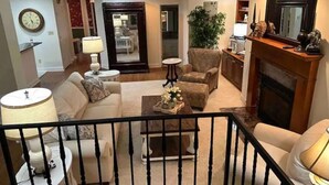 A living room with a sofa, armchairs, a coffee table, and a fireplace. There is a clock on the wall and a plant in the corner. - Plenty of room near square (Oxford)