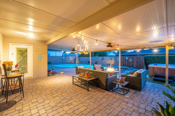 Relax on the patio with a sofa, chair, and table, surrounded by a swimming pool and hot tub.