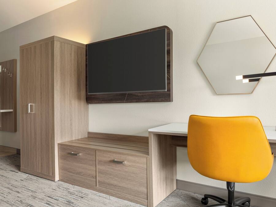 A modern bedroom with a wooden wardrobe, a bed, and a desk with a chair.