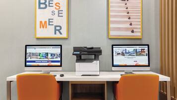 Un'area lavoro con due monitor, una stampante e due sedie arancioni.