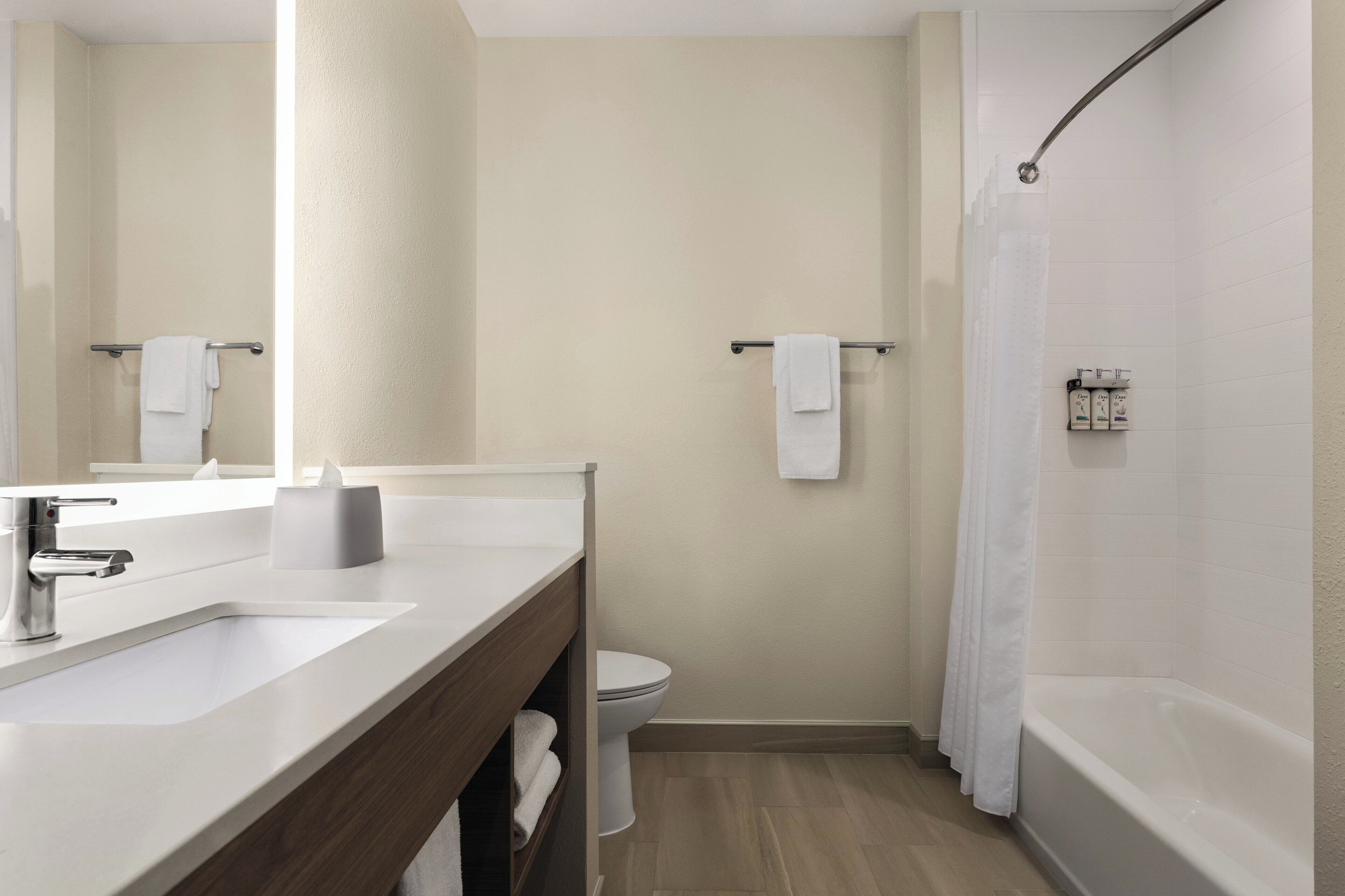 A modern bathroom with a sink, mirror, toilet, and bathtub.