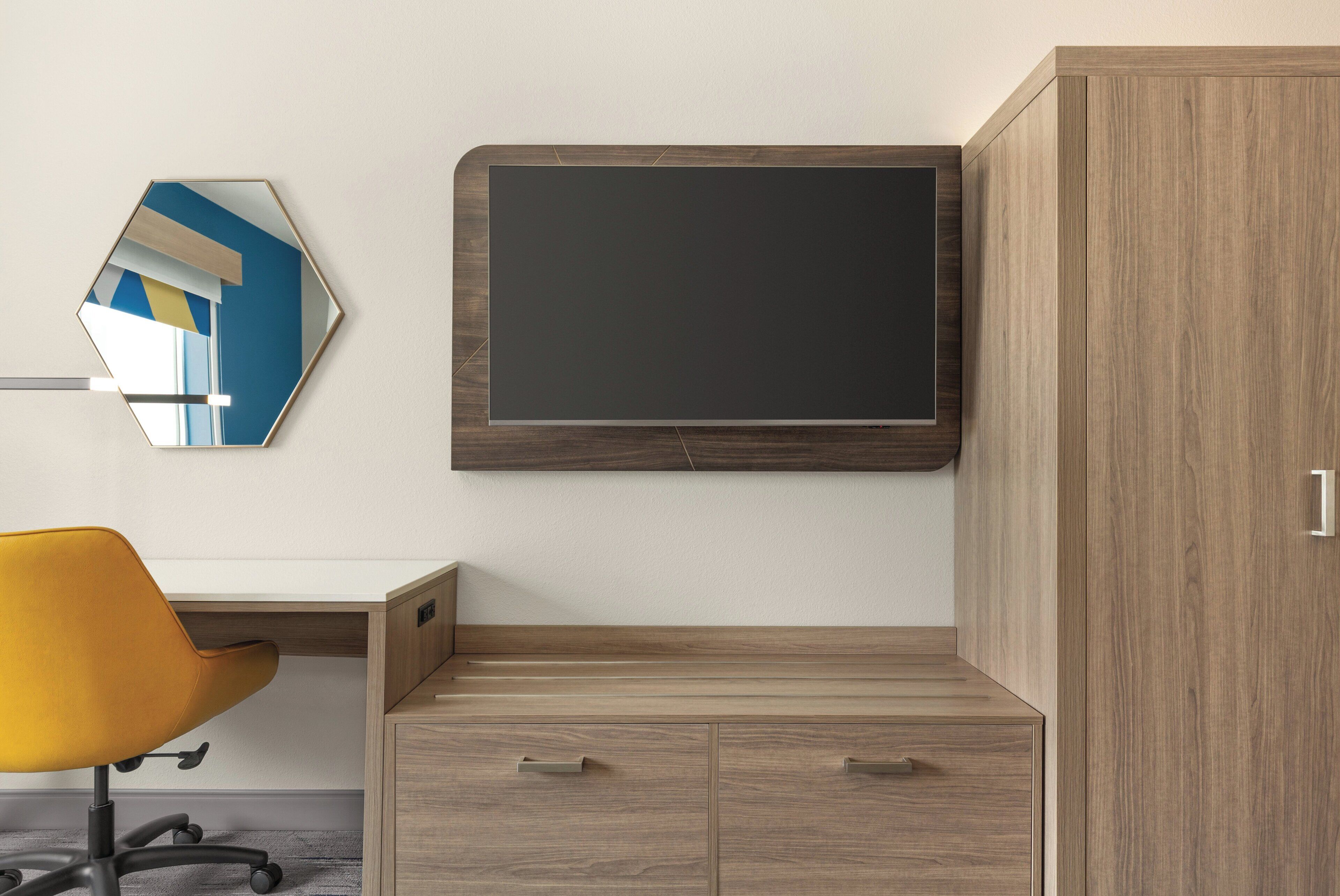 A modern office space with a desk, chair, and a mounted TV.