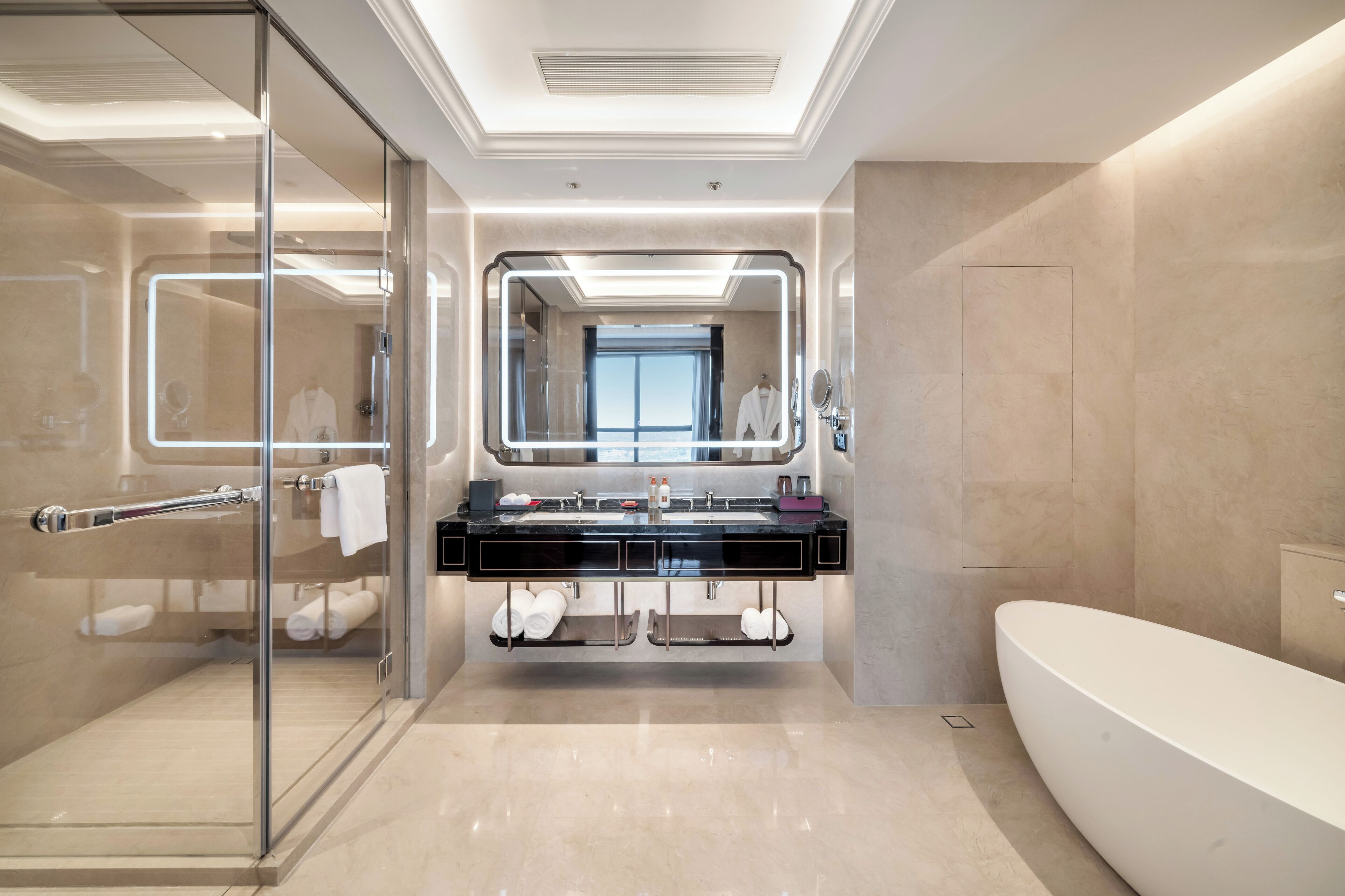 A modern bathroom with a glass shower enclosure, a large mirror, a black vanity with a sink, and a freestanding bathtub.