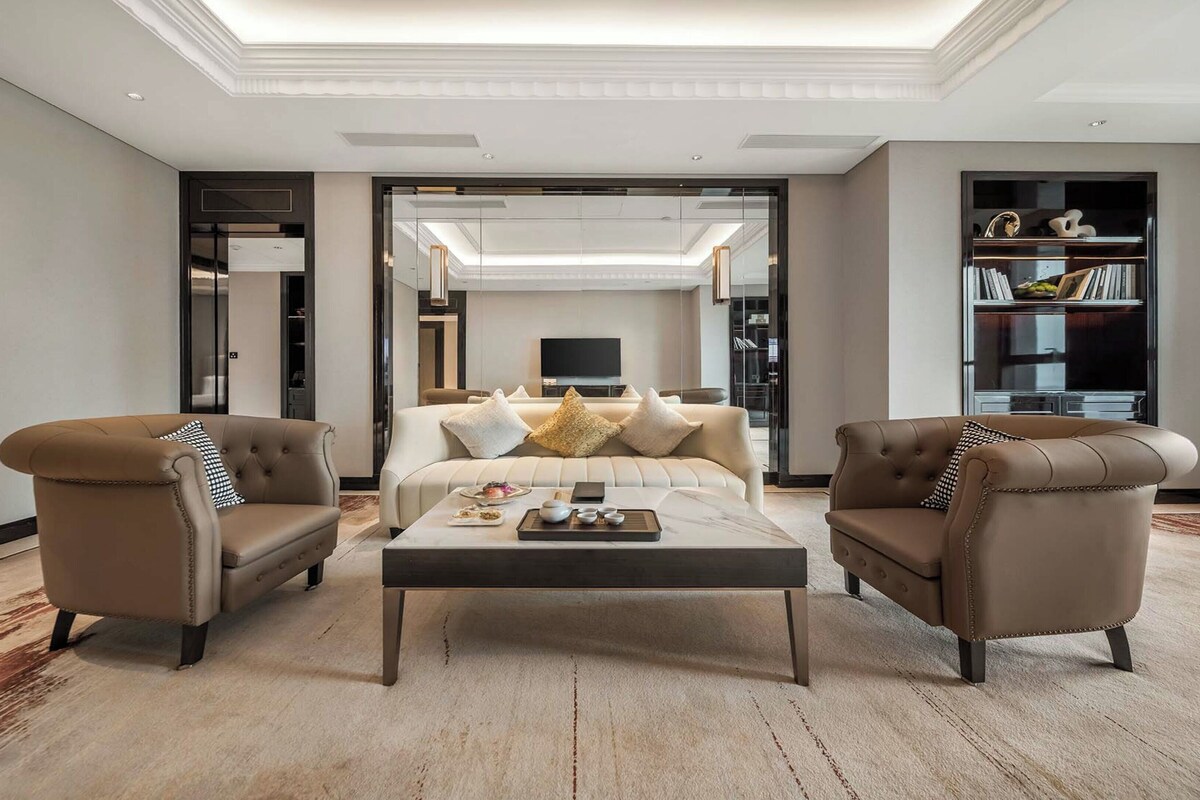 Un salon moderne comprenant un canapé, deux fauteuils, une table basse et une bibliothèque.