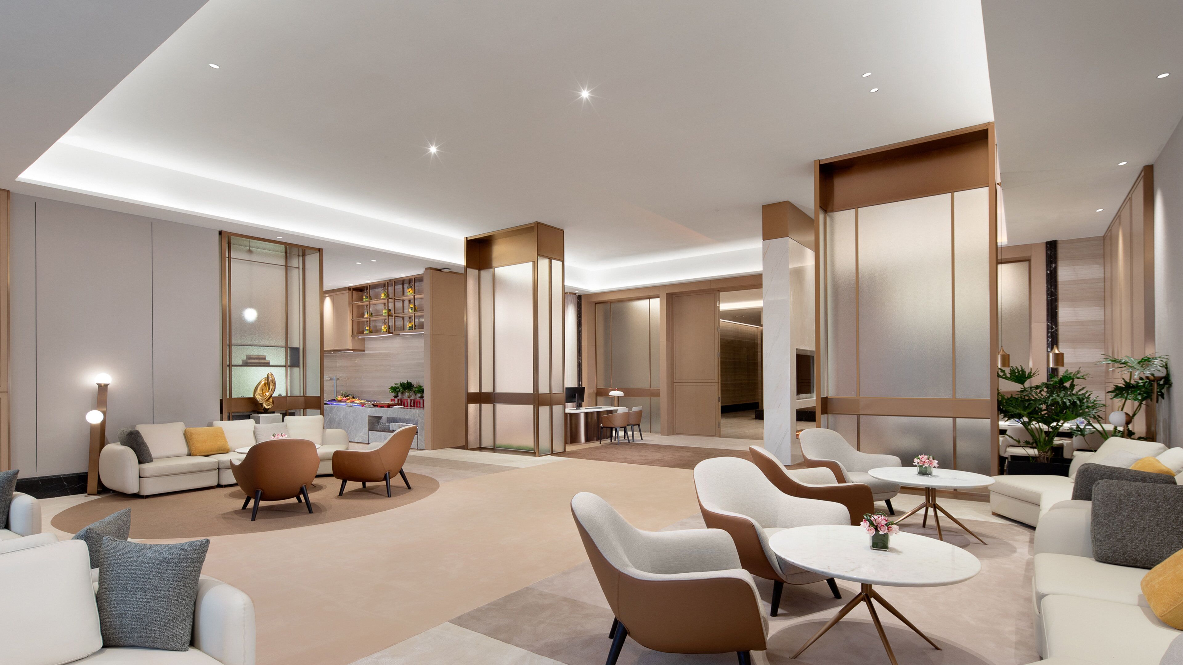 Un hall d’hôtel spacieux et moderne, doté d’un espace salon central, d’une kitchenette et d’une salle à manger séparée.