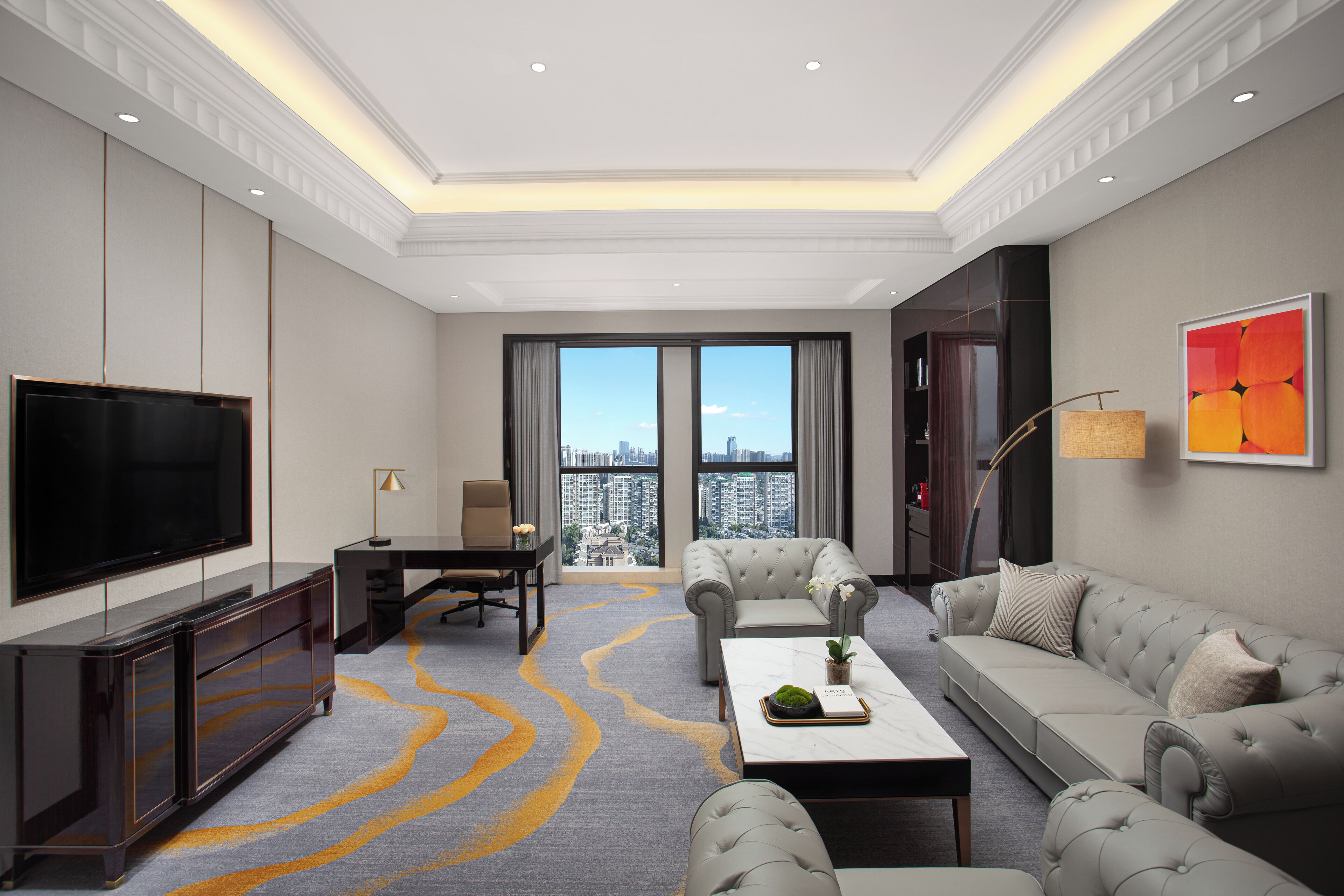A modern living room with a large flat-screen TV, a sofa, a coffee table, and a view of a cityscape through large windows.