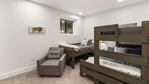 Un dormitorio con literas, un sofá y una ventana pequeña.