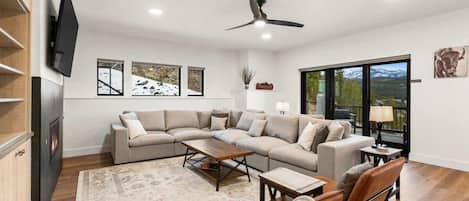 A modern living room with a sectional sofa, a coffee table, and a fireplace.