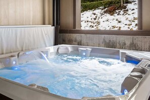 Ein Whirlpool mit Blick auf eine verschneite Landschaft durch ein Fenster.
