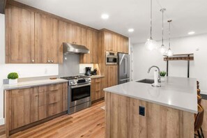 Een moderne keuken met houten kastjes, roestvrijstalen apparatuur en een centraal eiland.
