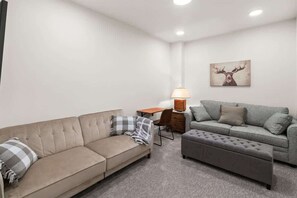 Ein Wohnzimmer mit zwei Sofas, einem kleinen Tisch, einer Lampe und einem Bild an der Wand.