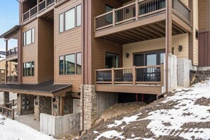 A multi-story building with balconies, stone pillars, and a snow-covered ground. - Ski-in/Ski-Out Slopeside Luxury Condo in Big Sky (Big Sky)