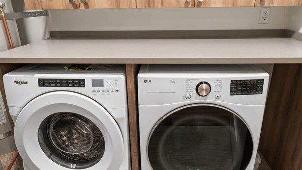 Dos lavadoras de carga frontal, Whirlpool y LG, instaladas debajo de una encimera de cocina.