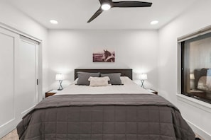 A bedroom with a bed, two bedside lamps, a ceiling fan, a window, and a wall-mounted picture. - Ski-in/Ski-Out Slopeside Luxury Condo in Big Sky (Big Sky)
