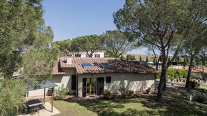 Ein Haus mit Ziegeldach, Solaranlage und einer kleinen Terrasse mit Tisch und Stühlen.