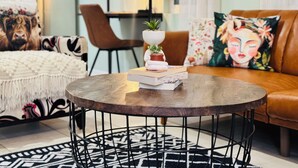 A cozy living room with a round coffee table, a sofa, a chair, and a decorative pillow.
