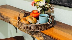A framed black and white photograph of a bull, a basket with bread, a candle, and a vase with flowers on a wooden counter.