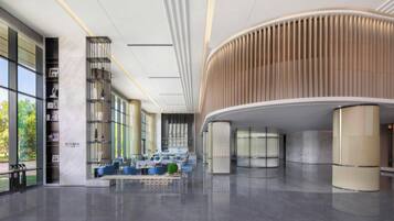 A spacious lobby with a curved wooden ceiling, a seating area with blue chairs, and a bookshelf labeled "LOUNGE".