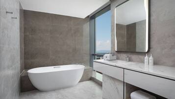 A modern bathroom with a freestanding bathtub, a large mirror, and a view of the city.