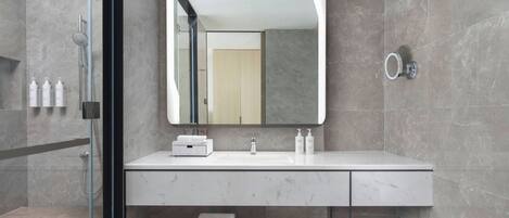 A modern bathroom with a glass shower enclosure, a white marble sink, and a large mirror.