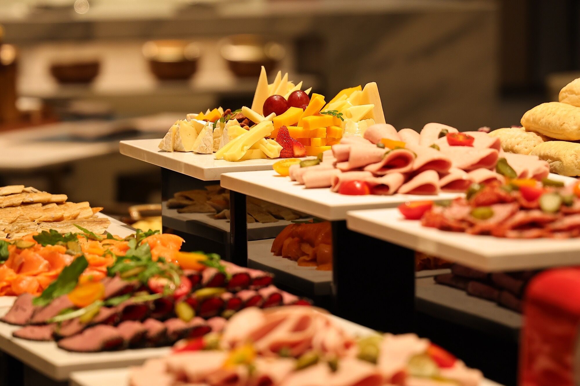 Un buffet proposant une variété de plats, notamment des viandes, des fromages et des fruits.