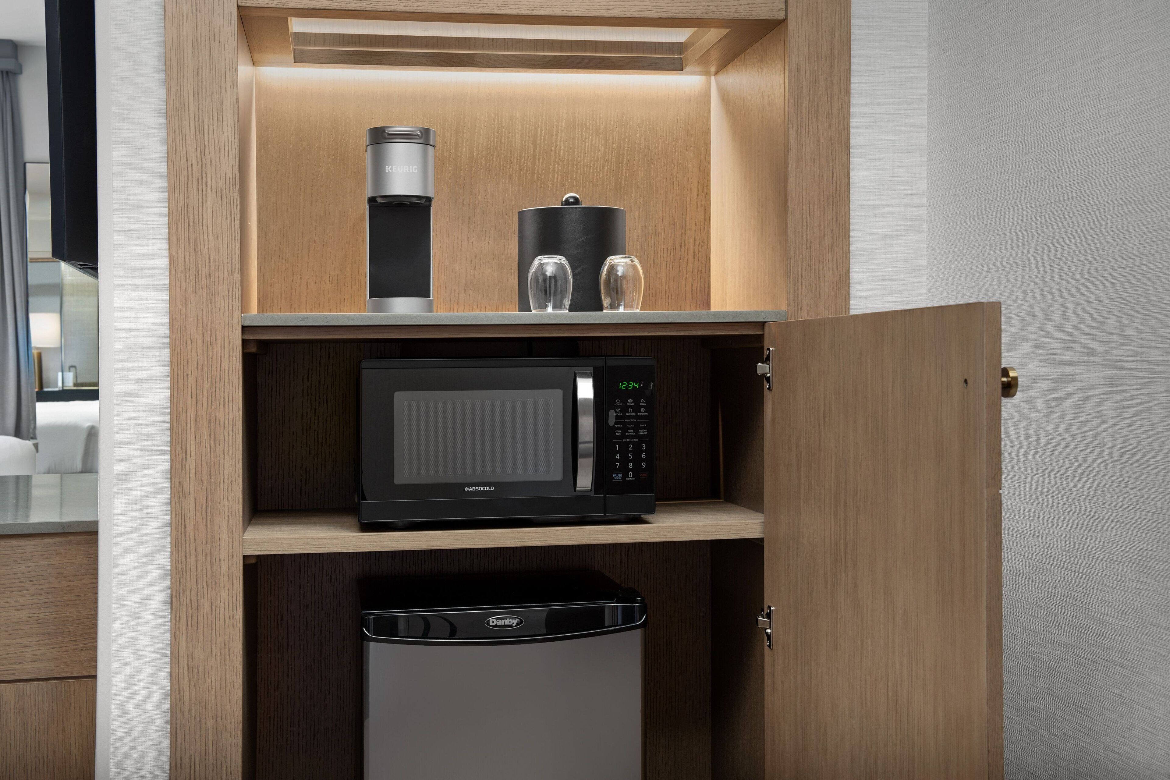 Une cuisine compacte équipée d’un four à micro-ondes, d’une machine à café et d’un lave-vaisselle.