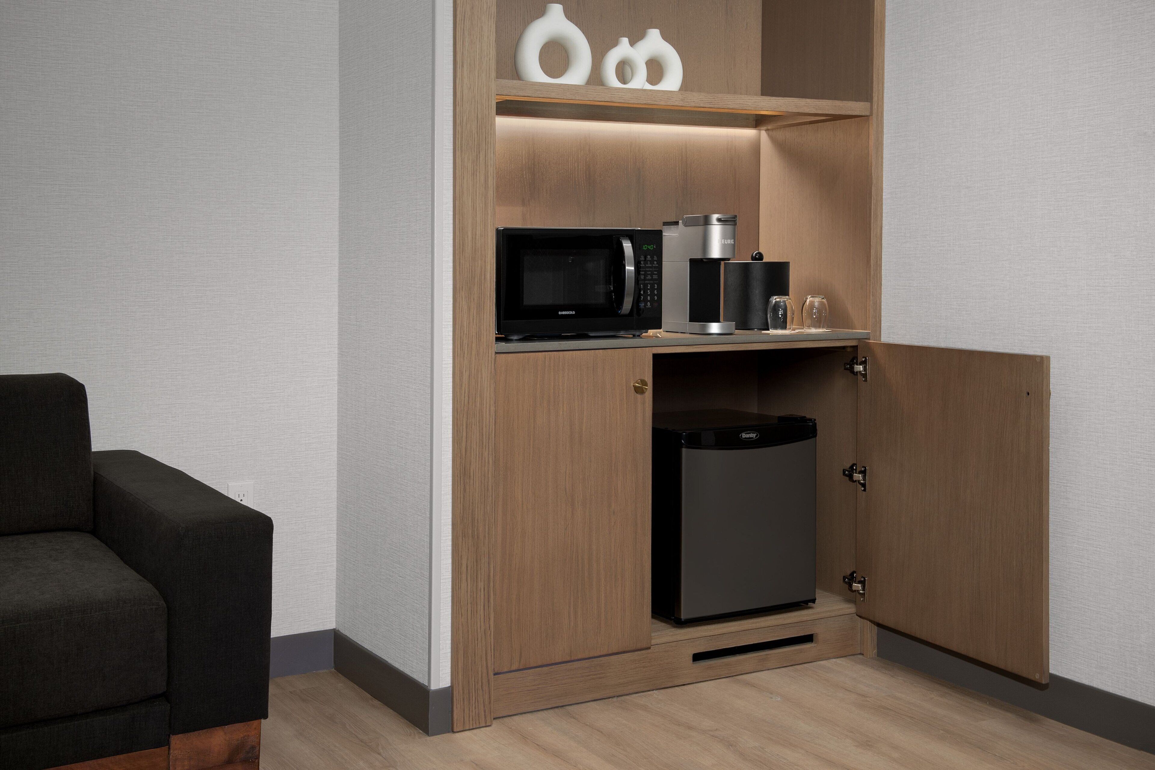 A compact kitchenette with a microwave, coffee maker, and refrigerator.