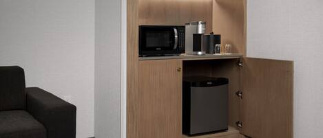 A compact kitchenette with a microwave, coffee maker, and refrigerator.