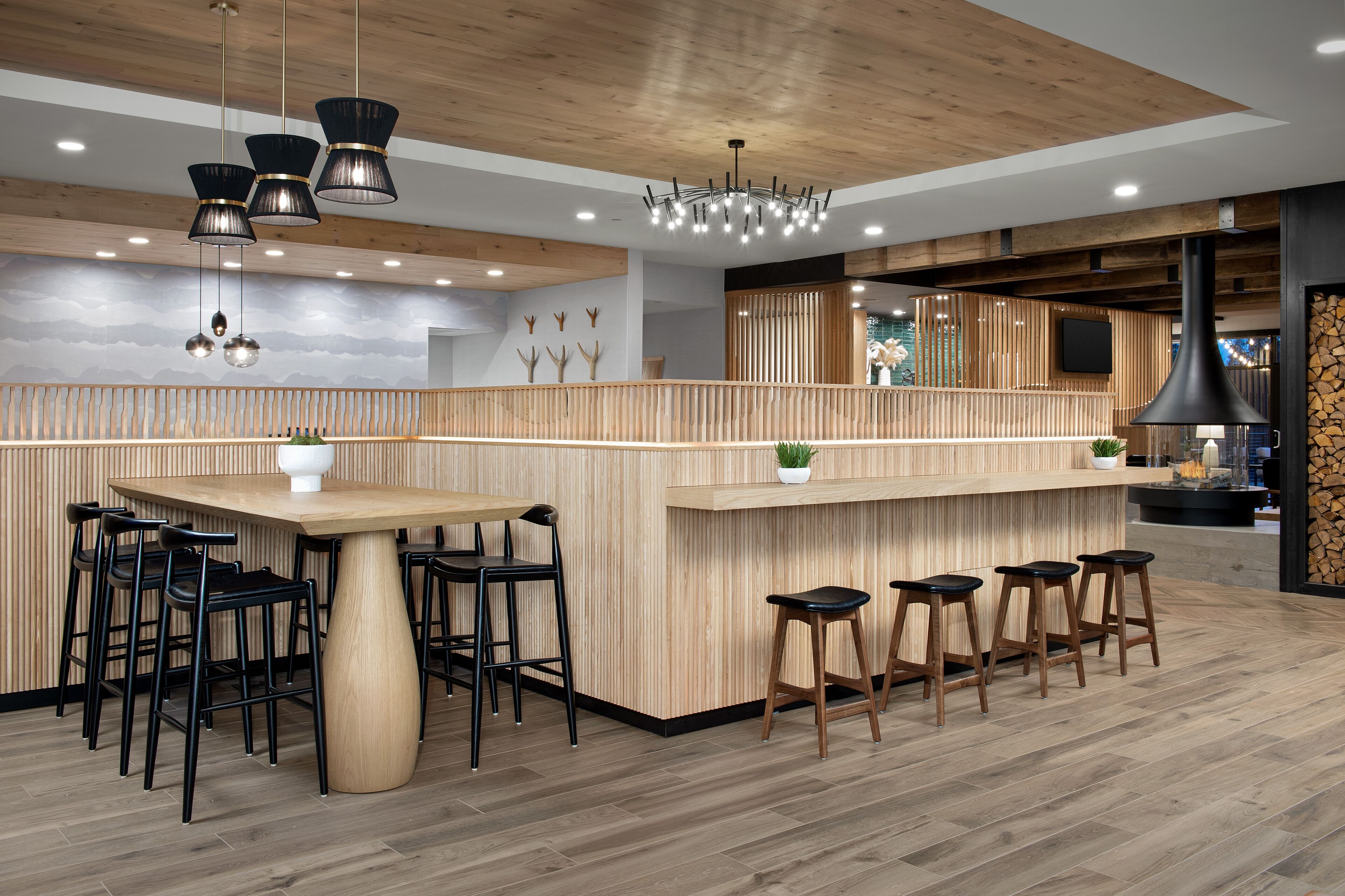 A modern kitchen with wooden accents, a central island with stools, and pendant lighting.