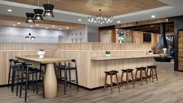 A modern kitchen with wooden accents, a central island with stools, and pendant lighting.